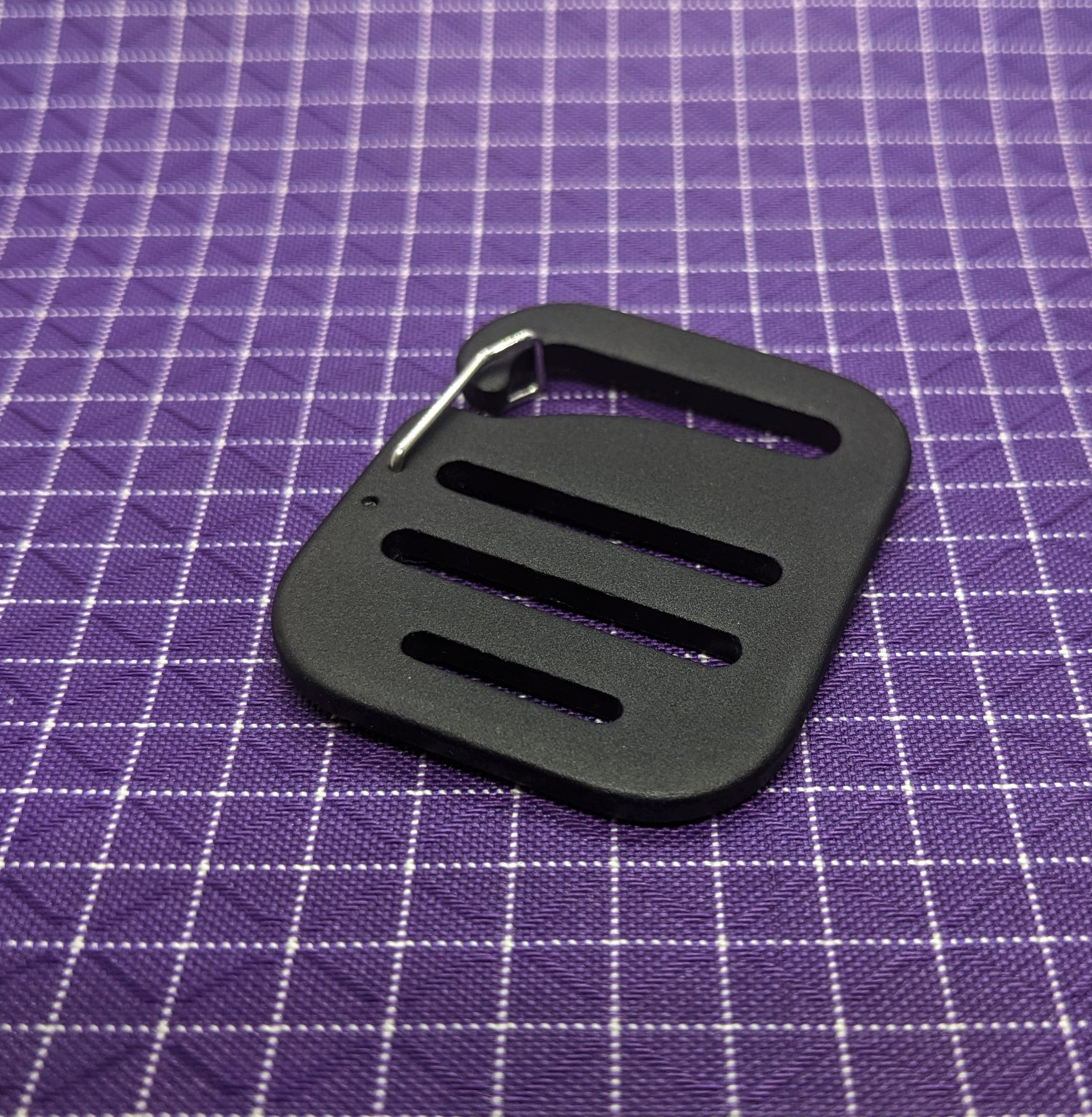 This is a high-quality, aluminum G-hook gatekeeper that can be paired with webbing strapping and used when making or modifying bags and packs. These are nice because the metal clip keeps the buckle from falling off the webbing when there is no tension to the strap.