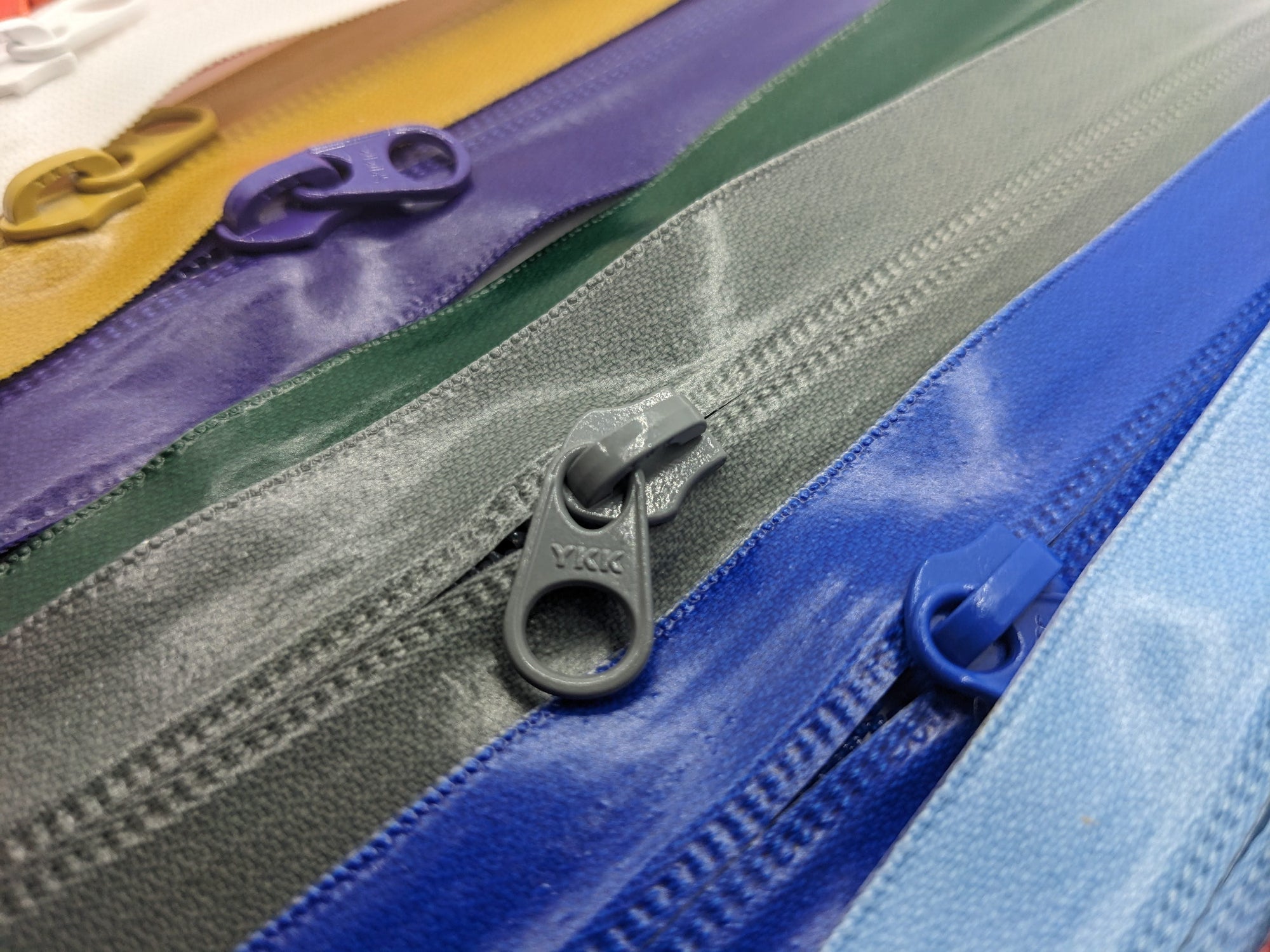 YKK's AquaGuard® NATULON® series is an eco-friendly water-repellent zipper option created by laminating polyurethane (PU) on the non-coil, reverse side of a zipper. The NATULON style is the new sustainable standard for all YKK Aquaguard products.   YKK's AquaGuard® NATULON® updates include:  Recycled polyester tape (which helps reduce CHG emissions) PFC free water repellant finish 20-40% smoother in operation force New smoother appearance